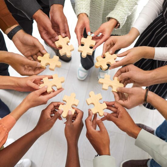 A group of people standing with a puzzle piece in their hands forming a circle