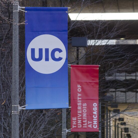 Two banners hanging from poles. The first banner is blue with the UIC logo, the second banner is red with text reading 